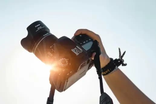 A DSLR camera raised against the sun