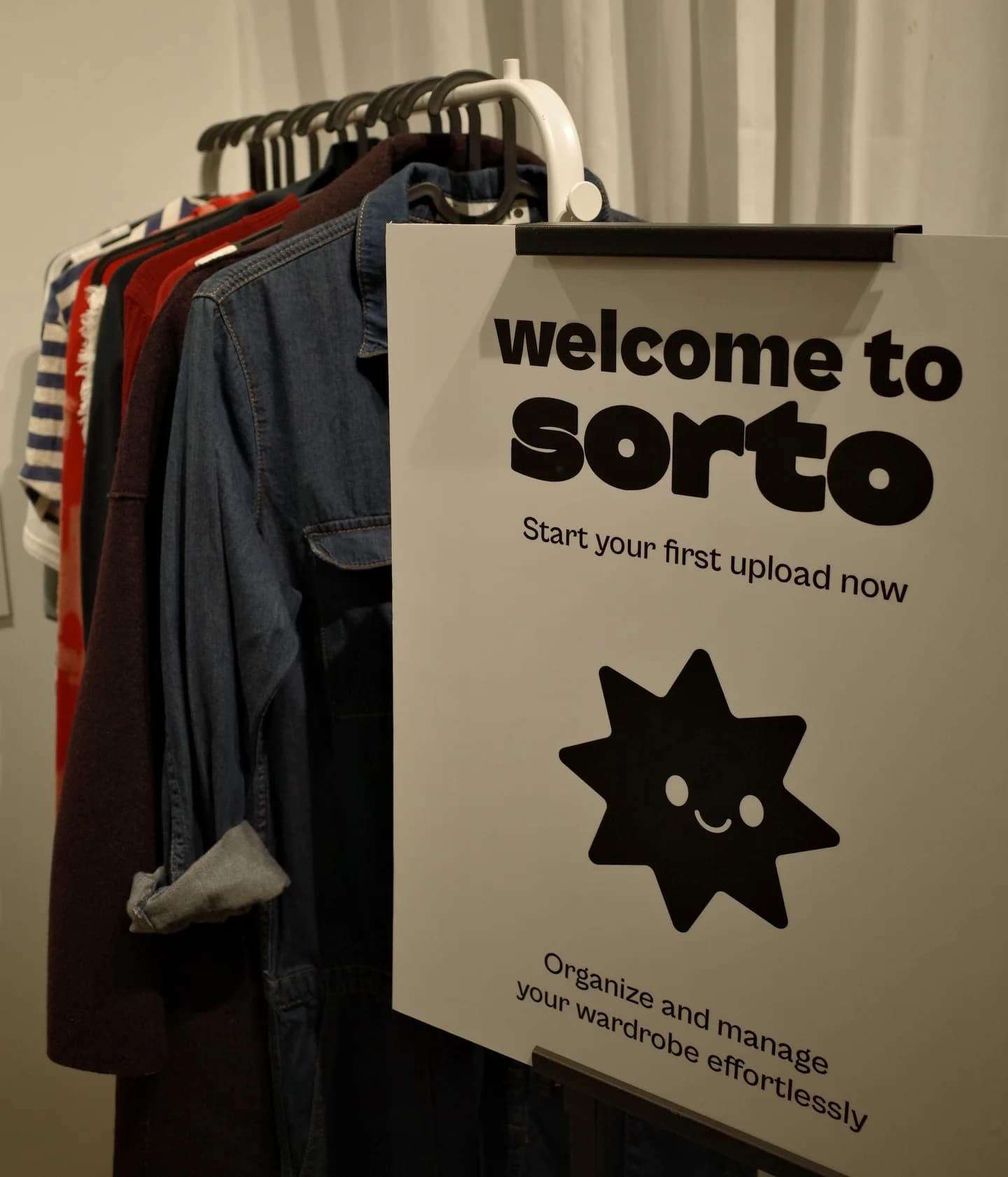 Welcome to sorto sign hanging on a clothing rack, inviting users to start their first upload